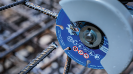 A diamond cutting wheel slices through a steel rebar at a construction site.