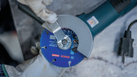 Person wearing safety equipment tightens the blade on an angle grinder.