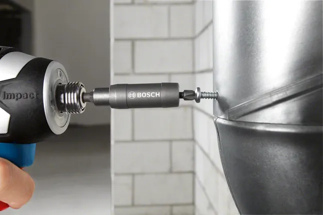 A power tool drives a screw into a metal surface.